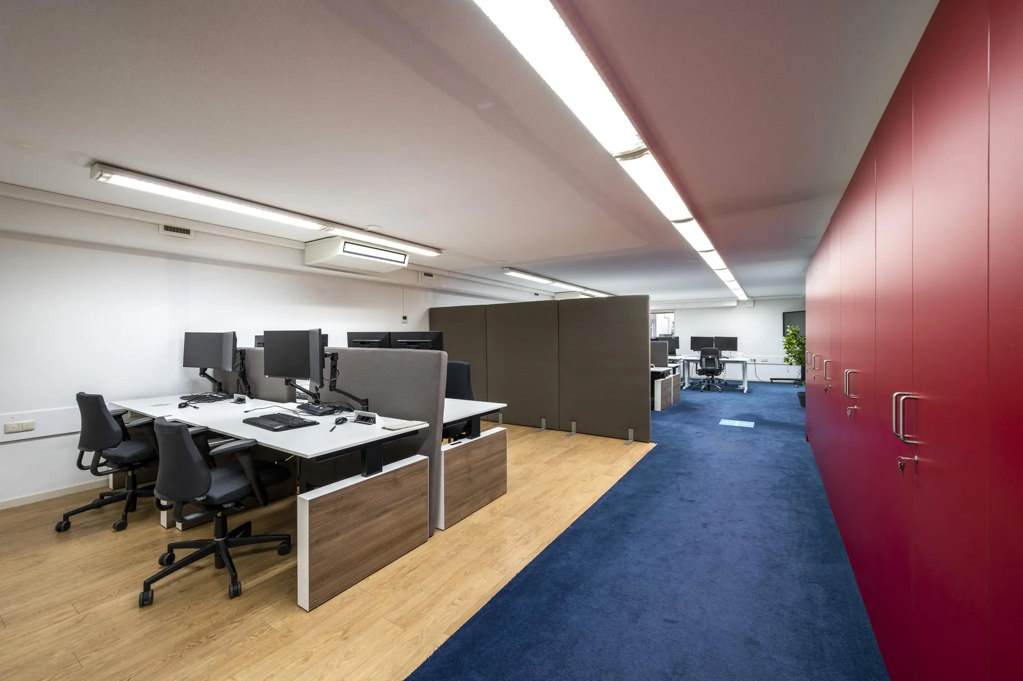 Modern kantoorinterieur aan de Prins Hendrikkade met werkplekken, scheidingswanden en rode opbergkasten.